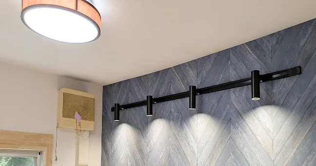 ブルーのヘリンボーン柄アクセントクロスとダクトレールによる照明演出