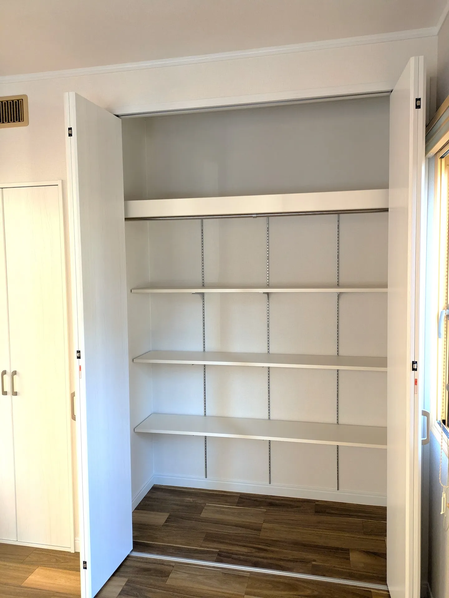 高さ調整可能な可動棚とハンガーパイプを備えた、扉を開けた状態のクローゼット