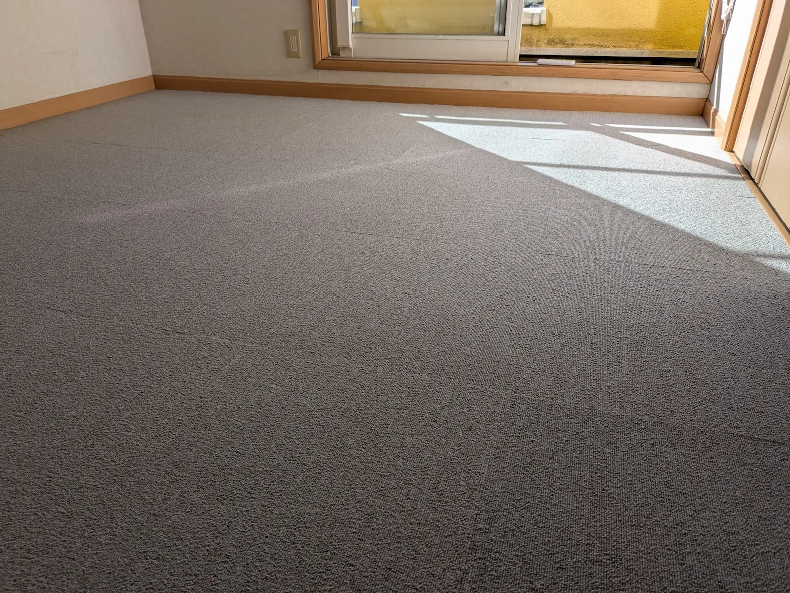 壁際まで隙間なく綺麗に施工されたグレーのタイルカーペット