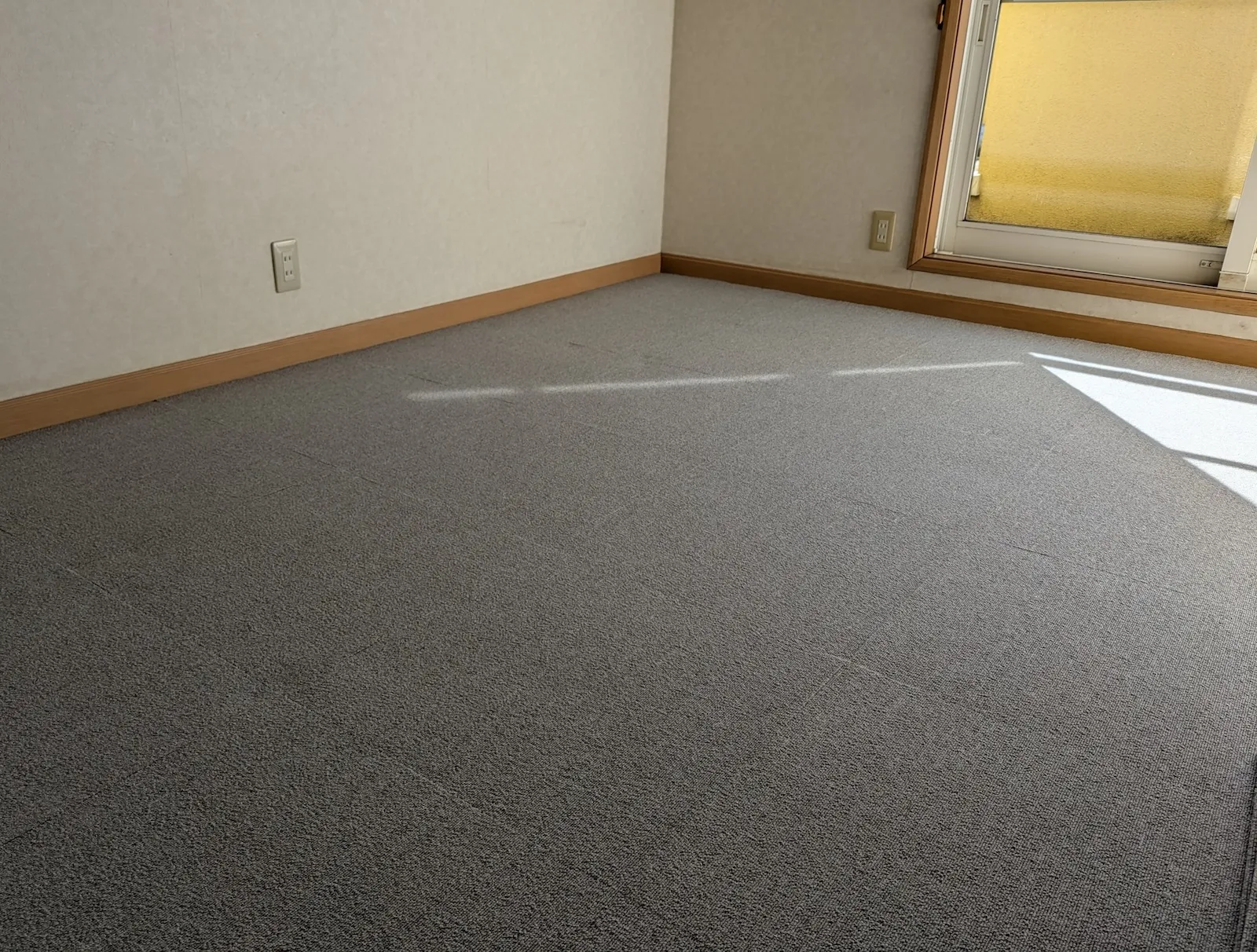 壁際まで隙間なく綺麗に施工されたグレーのタイルカーペット