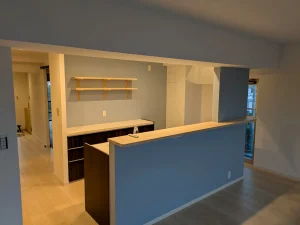 機能美を追求したカウンターキッチンのリノベーション。ブルーの壁紙と造作棚のあるモダンな空間
