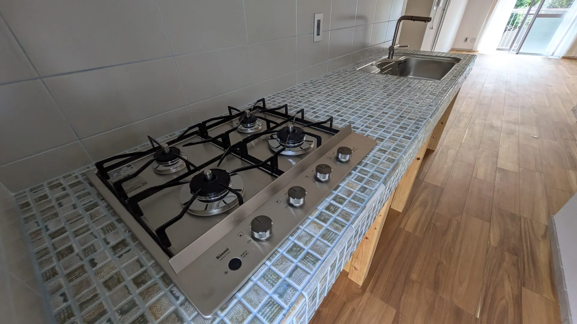 モザイクタイルの天板に埋め込まれた4口ドロップインコンロ