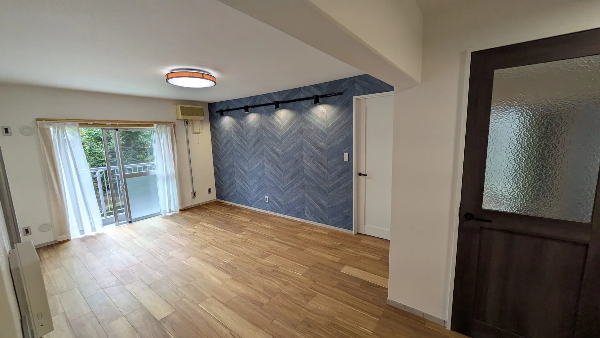 ヘリンボーン柄のアクセントウォールがおしゃれなリビング。開放的な空間デザイン。