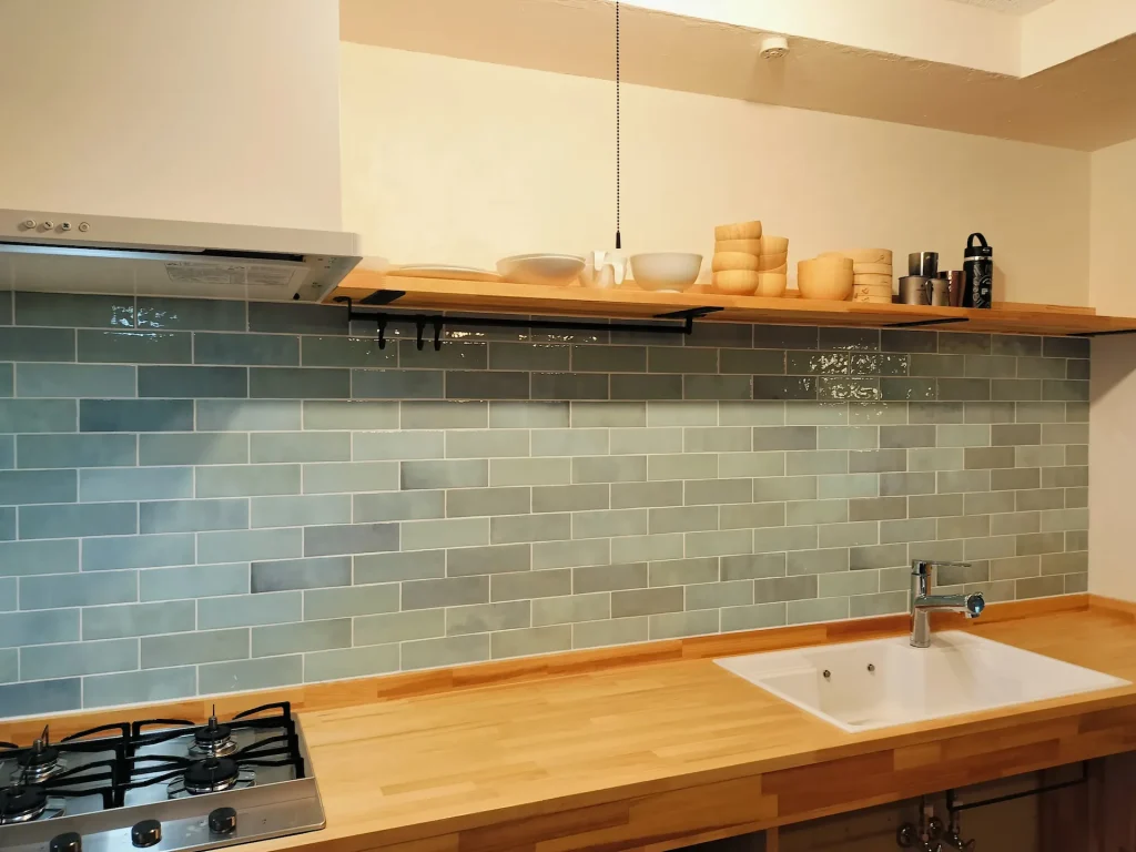 淡いブルーのサブウェイタイルと無垢材の飾り棚