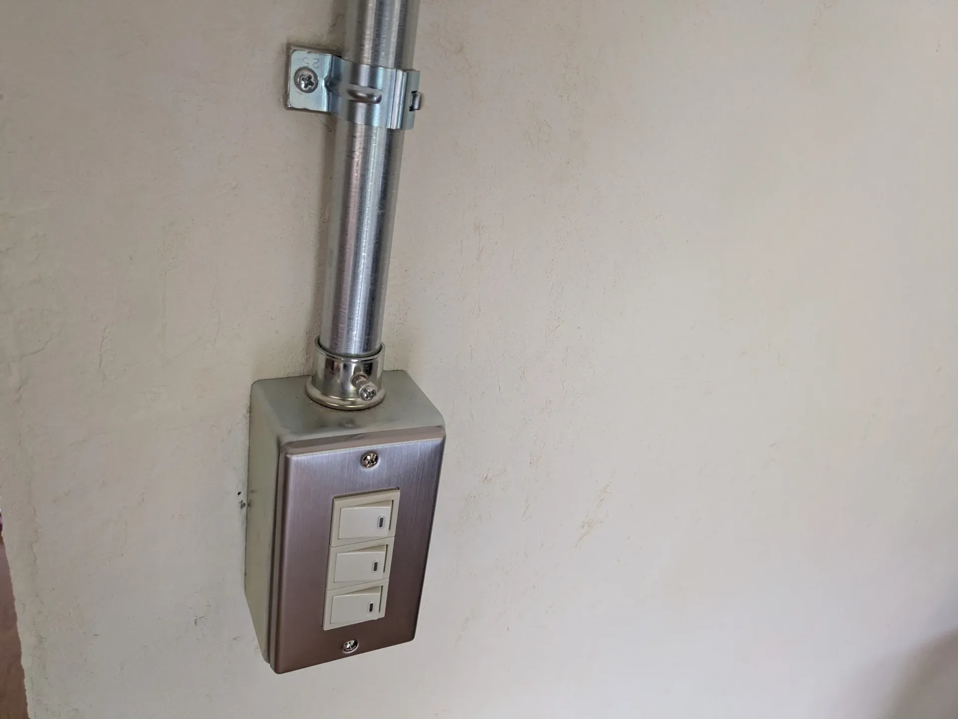 金属配管に直結された露出型スイッチボックスとステンレスプレート