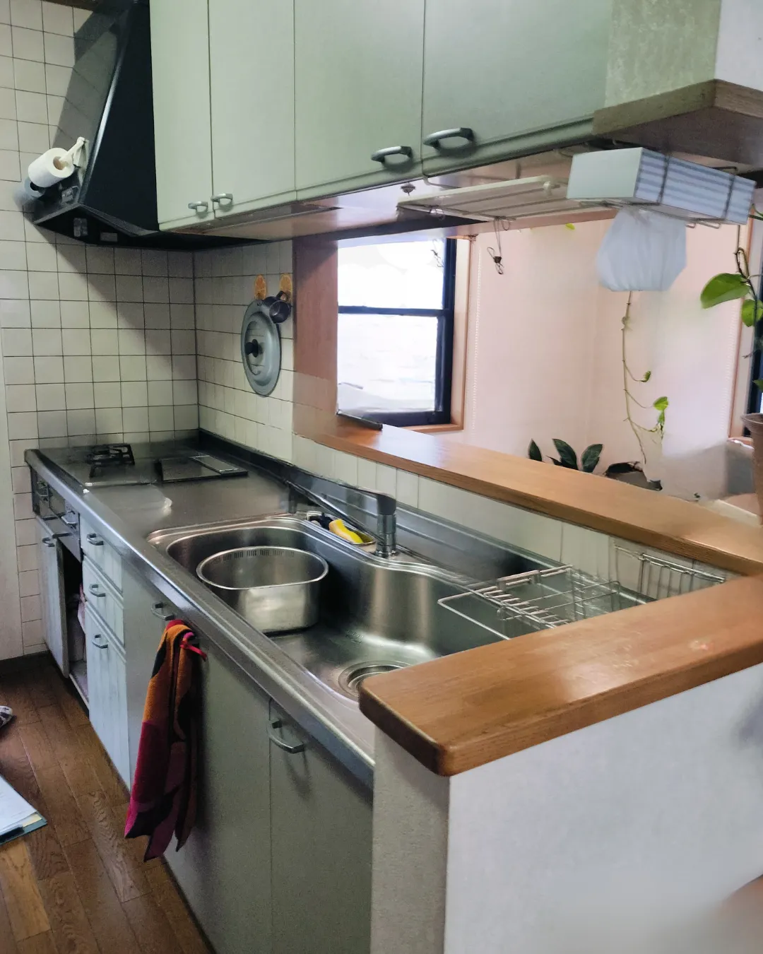 施工前の薄い緑色のタイル壁と古いキッチンキャビネット