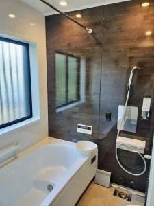 ダークブラウンのアクセントパネルが映えるモダンな広々とした新しい浴室